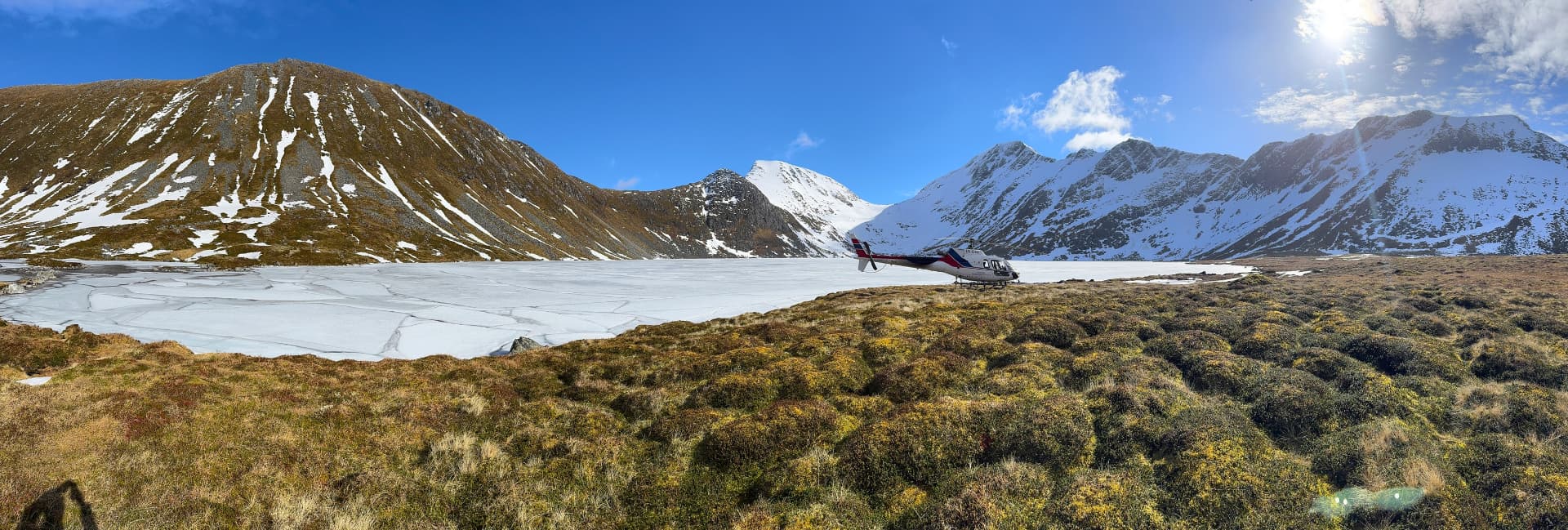 Helikopter ved islagt fjellvann under linjeinspeksjon